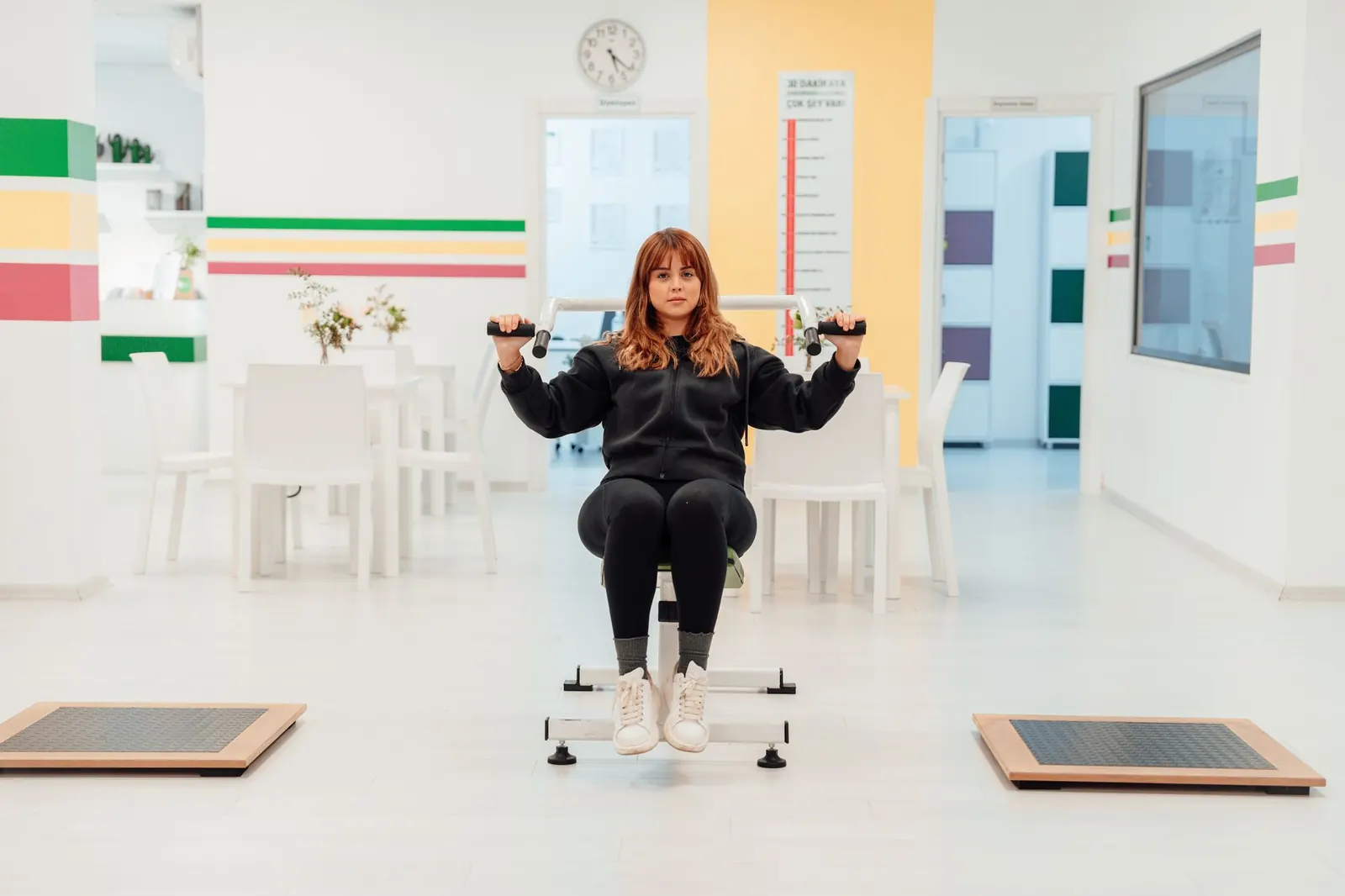 Bright rehabilitation gym with a patient on a seated exercise machine